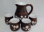 ILONA, Monte Verde - MG - Jarra e 4 copos em cerâmica, decoração patinada em marrom, aplicada com flores, interior craquelet. Assinada no fundo pela ilustre artista húngara que se estabeleceu na cidade mineira. Jarra 21 x 19 x 12cm, alt. copo 10cm.