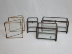 Cinco caixinhas mostruário em vidro translúcido, estrutura em metal amarelo. Uma com pé quebrado, apresenta desgastes. Maior 8 x 16 x 7cm, menor 9 x 9cm.