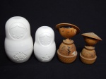 Três figuras de bonecos: dois decorativos em madeira, japoneses, alts. 10 e 8cm; e bonecas Matrioska em plástico, medidores, alt. total 12cm.