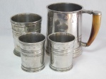 JOHN SOMMERS - Quatro peças em estanho polido: caneca com alça em chifre, copo maior e 2 copos menores. Apresenta desgastes e marcas do tempo. Marcados. Alt. maior 11cm, alt. menor 7cm.