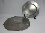 JOHN SOMMERS - Duas bandejas em estanho, sendo 1 oitavada aplicada com flores-de-lis, e 1 com 4 pés, bordas onduladas. Apresentam desgastes. Diâms. 26 e 30cm.