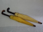 Duas antigas sombrinhas infantis, uma com cabo em madeira revestida em couro, um com cabo em resina preta. Desgastes no couro e marcas do tempo. 59 e 57cm.