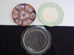 Três pratinhos distintos: a) Em porcelana, decorativo, fundo vermelho e azul, decoração de flores e pássaros no padrão chinês. Diâm. 16cm. b) Em porcelana inglesa, para sobremesa, borda ondulada, faixa em verde. Marcado John Maddock & Sons. Diâm. 18cm. c) Para bolo pequeno, em vidro, borda ondulada, fundo moldado em alto relevo com flores. Diâm. 19cm.