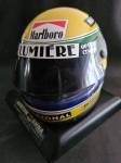 Capacete Tricampeão de Airton Senna em replica, escala reduzida (15 x 11cm), base giratória com discretíssima mossa no lado esquerdo, no estado, ítem raro.