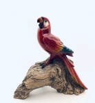 Arara vermelha repousando sobre tronco, confeccionada em resina italiana. Med. 16x15 cm.