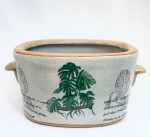 Cachepot em porcelana decorado com coqueiros, com duas pegas laterais. Med. 13x31 cm.