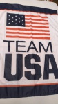 Lindo Banner ou bandeira com a bandeira dos estados unidos e tema do time olímpico americano. Eles colocam essas peças na frente das casas em época de jogos olímpicos. Mede 92cm de altura por 69cm de largura. Pintura meio emborrachada, tem dois pequenos cortes em cima do A