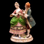 Estatueta de porcelana policromada japonesa, representando figura de casal em cena galante. Marcas da manufatura no fundo da peça. 19 x 14 x 9,5 cm.