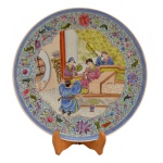 Prato raso de porcelana japonesa policromada apresentando decoração com predominância na cor azul.  Centro com personagens em trajes típicos. 33 cm.