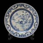 Prato de porcelana chinesa apresentando decoração vegetal com esmalte azul, sobre superfície branca. Borda circular decorada com guirlandas e centro com paisagem. China. No fundo selo da coleção: Nobrega Antiguidades.