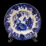 Conjunto de dois pratos de porcelana inglesa, sendo: A) Borda recortada com pontilhados e motivos florais. Centro com vista de Castelo Inglês. No fundo marcado: John Son Bros, England. Old Britain Castles. Ironstone.  B) Superfície de fundo branco com decoração em tons de azul cobalto. Borda ondulada com larga faixa com arabescos e centro com pássaros, castelo e jardim.