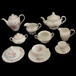 Serviço para chá e café em porcelana nacional. No fundo marcas da manufatura: Porcelana Schmit, Santa Catarina. Made in Brasil. Constando de: bule para chá (16 cm), açucareiro (9 cm), cremeira (10 cm), leiteira (9 cm), bule para café (17 cm), manteigueira (15 x 9 cm), açucareiro sem tampa (6 cm), 5 xícaras para chá com pires (6 x 11 cm / 15 cm pires) e 5 xícaras para café com pires (5 x 7 cm / 11 cm o pires).