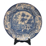Medalhão em porcelana inglesa, apresentando decoração em azul e branco com arvores, pagodes e jardim. No fundo marcado Enoch 1784, Ralph 1750, Woods, Burslem, England. 41 cm.