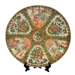 Prato em porcelana chinesa decorada em esmaltes policromados no padrão Mandarim com cenas palacianas. Centro com reservas apresentando flores, frutas e borboletas. Séc. XIX. 37 cm.