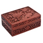 Caixa retangular em madeira em tom avermelhado, entalhada em alto relevo em toda a volta. Tampa igualmente em alto relevo com desenhos de ramos de folhas e flores sobre fundo quadriculado. Interior em preto. 4,5 x 11 x 7 cm.4,5 x 11 x 7 cm.