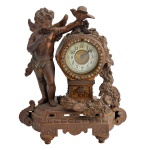 Relógio de mesa ornamentado por escultura em bronze patinado representando anjo com guirlanda florida. Centro com mostrador em esmalte branco e borda com pedrarias. Base oblonga com frisos geométricos e vazados apoiada em pequenos pés retos. 21 x 18 x 10 cm.