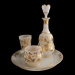 Verre dEau - Conjunto para noite em opalina francesa, com decoração de frisos e folhagens em ouro. França. Séc. XX. Constando de: 1 prato circular (20 cm); 1 garrafas (32 cm); 1 copo (13 x 8 cm) e 1 pote (9 x 9 cm).