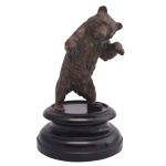 Estatueta em bronze austríaco, patinado representando urso apoiado em base de madeira circular. Séc. XX. 15 cm (escultura). 21 cm com base.