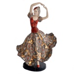 Estatueta em porcelana alemã policromada representando bailarina com saia esvoaçante. No fundo marcas da manufatura: Goldscheider. Made in Germany. 33 x 21 x 12 cm.