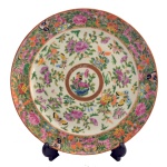 Prato em porcelana chinesa profusamente decorada em policromia de esmaltes no padrão Mandarim com flores e borboletas. Borda com fundo dourado e centro com pequeno medalhão de mesmo estilo. Séc. XIX. 24 cm.