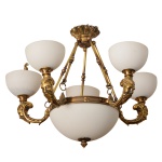 Lustre com estrutura em bronze com imagens de rostos masculinos contando com cinco pontos de iluminação ao redor e uma central, cúpulas opalinadas em formato côncavo. 50 x 55 cm.