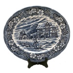 Travessa oval em porcelana inglesa, na tonalidade azul e branca com decoração de cena de caçada. No fundo marcas da manufatura: Hand Engraved by W. N. Mellor. Royal Tudor Ware, Sttanffordshire, England. 33 x 28 cm.