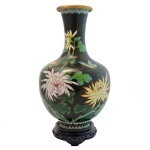 Vaso em metal cloisonné, estampas de flores sobre fundo preto, apoiado em base de madeira em tom preto cerejeira. 31 cm. Base de madeira 4 cm.