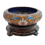 Centro de mesa em metal cloisonné, trompe loeil em alto relevo sobre fundo dourado, fundo interno decorado com arranjos florais, base em madeira marrom. 6 x 16 cm. Base 4 cm.