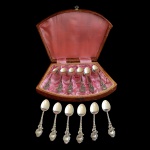 Conjunto de doze colheres em prata 800 acondicionado em estojo de madeira semicircular, forrado em seda rosa, com fecho trabalhado. 160 gramas.
