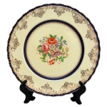 Prato em porcelana inglesa com bordas em azul cobalto e elementos decorativos dourado sobre fundo creme apresentando ao centro bouquet floral. No fundo as inscrições: Grindley, England, Cranmere. 23 cm.