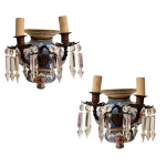 Par de apliques em porcelana italiana Capodimonte, em tonalidade azul royal, decorada por figuras de anjos e flores e aplicações em dourado. Pingentes de cristal Baccarat. Dois pontos de iluminação cada e guarnições em bronze.