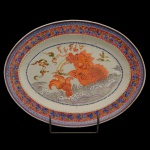 Travessa oval em porcelana chinesa da Companhia das Índias, ornamentada em esmaltes policromados por borda com folhas de parreira e cachos de uva. Centro apresentando cena marinha com peixe-dragão no meio de ondas. China. Qing. Reinado Qianlong (1736-1795). 30 x 33 cm.