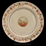 BARÃO DE PAQUETÁ - Prato circular em porcelana Cia das Índias, pertencente ao Serviço do Barão de Paquetá (José Tomás da Silva Quintanilha) proveniente da família do Marques de Olinda. Fundo branco decorado por paisagem rural em reserva única central, circundado à borda por arabescos e guirlandas floridas em rica policromia de esmaltes. China. Dinastia Qing (1644 - 1911). Jiaqing (1796 - 1820). 25 cm. Reproduzido na pág. 199 /2 20 do livro As Cias das Índias e a Porcelana Chinesa de Encomenda, por José Roberto Teixeira Leite.