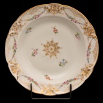 D. PEDRO II - SERVIÇO DO CASSINO FLUMINENSE - Prato fundo e circular em porcelana francesa. Sem marcas. Borda decorada com guirlandas de flores em policromia e arabescos dourados entre frisos dourados, centro da caldeira com roseta dourada com ramos de flores em policromia. Séc. XIX. 23 cm. Peça do mesmo serviço reproduzida à pág. 228 do Livro "Louça da Aristocracia do Brasil", por Jenny Dreyfeus.