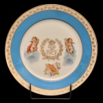 REI LOUIS PHILIPE - Raro prato de porcelana francesa de Sèvres, decorado com frisos a ouro sobre proeminente faixa azul royal, centralizando anjos e o monograma Real de Louis Philipe sob coroa. No verso marca de Sèvres e chancela do "Chateau des Tuileries". Numerado 45 com selo em vermelho ao fundo, excepcionalmente marcado com a marca suplementar representando a coroa real francesa. Séc. XIX. 23 cm.