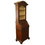 Elegante bookcase estilo inglês em madeira nobre, ornado com frisos em debrum. Tampo reclinável revelando parte interna com gavetinhas e escaninhos. Caixa retangular com armário. Alçada reta com porta envidraçada e prateleiras internas. Frontão recortado com frisos salientes. Saia apoiada em largos pés baixos. 192 x 59 x 40 cm.