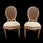 Par de cadeiras, estilo Louis XVI, em madeira patinada, ornamentadas por frisos esculpidos com fitas estilizadas. Encostos ovalados, apoiados em assentos com frentes abauladas. Pernas dianteiras retilíneas e caneladas rematadas por anelados. Forração em palhinha. 96 x 50 x 45 cm. Apresenta restauro nas pernas. No estado.