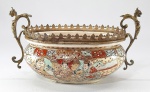 SATSUMA - Antiga floreira oval em porcelana japonesa, decorada com farta policromia e dourações, esmaltes em relevo. Assinado no fundo. Med. 14 x 22 x 12 cm. Guarnição em bronze.