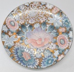 Prato em porcelana chinesa decorado com flores em esmaltes em tons pasteis sobre fundo dourado. Med. 26 cm.