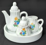 Antigo jogo de chá em porcelana branca decorada com flores. Medidas: Bandeja 15 cm, Bule 10 x 12 e menor 6 x 7 cm.