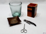 Lote composto de vaso floreira em vidro, porta treco em madeira, petisqueira em latão, tesoura e saca rolha em aço inox. Medindo a floreira 12,5cm de altura.