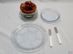 Lote composto de travessa redonda em vidro moldado, travessa redonda com alça em vidro, 2 espátulas para pasta e biscoiteira em vidro com tampa em resina. Medindo a travessa redonda 23cm de diâmetro x 3,5cm de altura.