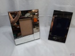 Lote de 2 porta retratos, sendo um espelhado e um em metal prateado. Medindo a moldura do espelhado 31,5cm x 26cm.
