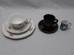 Lote composto de xícara de café em porcelana preta com detalhe grego, xícara de café tipo caipira azul com ouro e trio de chá com bolo em porcelana Real floral friso ouro.