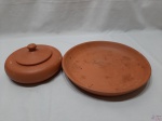 Lote composto de travessa redonda e farinheira em cerâmica crua. Medindo o prato 28cm de diâmetro x 4,5cm de altura. O prato está com um leve bicado na borda.