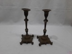Par de castiçais em bronze trabalhado com relevos. Medindo 9cm x 9cm x 21,5cm de altura. Pés pata de leão.