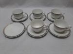 Jogo de 4 xícaras de café com 5 pires em porcelana Steatita, borda prata grega. Duas delas com bicado na borda.