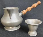 Duas peças em estanho, sendo leiteira e copo. Medindo respectivamente. Marcado ao fundo. 10 x 20 cm e 6 x 6,7 cm.<br>