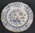 Meissen - Prato em porcelana alemã, da manufatura de Meissen, esmaltado na cor azul, decorado com fios de ouro, sobre fundo branco, do padrão dito Cebolinha e bordas onduladas. Medindo: 21 cm.