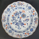 Meissen - Prato em porcelana alemã, da manufatura de Meissen, esmaltado na cor azul, decorado com fios de ouro, sobre fundo branco, do padrão dito Cebolinha e bordas onduladas. Medindo: 3,5 x 24 cm.